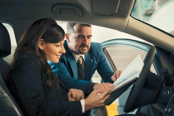Car dealer showing businesswoman contract  - Zdjęcie, obraz