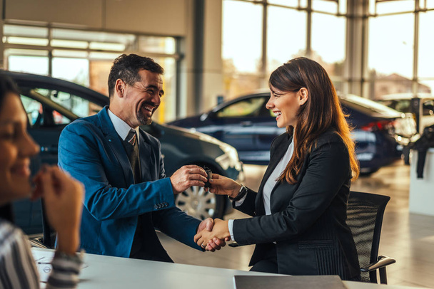 Salesman and customer shaking hands  - Фото, изображение