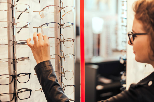 young woman is choosing new glasses - Foto, afbeelding