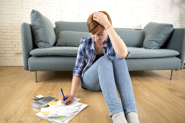 young sad worried and desperate woman banking and accounting home monthly and credit card expenses on living room floor - Photo, Image