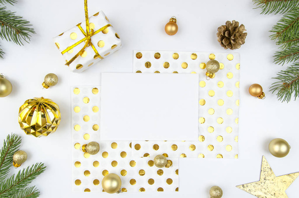 Romantic christmas composition. Paper blank, christmas tree branches, golden decorations and gift box on white background. Flat lay, top view, copy space, horisontal mockup - Fotografie, Obrázek