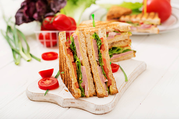 Club-Sandwiches mit Schinken und Käse auf Holzschneidebrett  - Foto, Bild