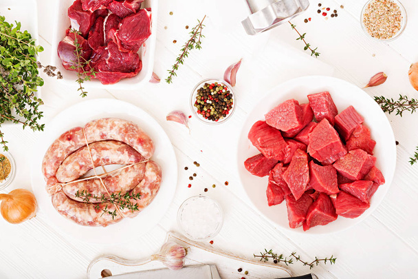 assiettes avec viande crue hachée et saucisses maison avec hachoir à viande sur la table, concept de processus de préparation de la viande forcée
   - Photo, image