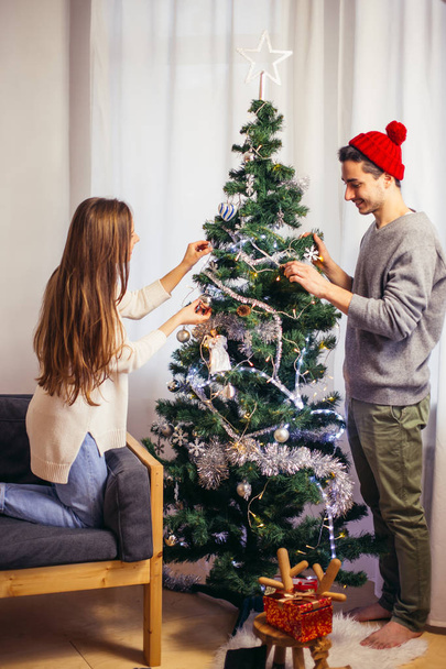 Cute, young couple decorating a Christmas tree - Zdjęcie, obraz