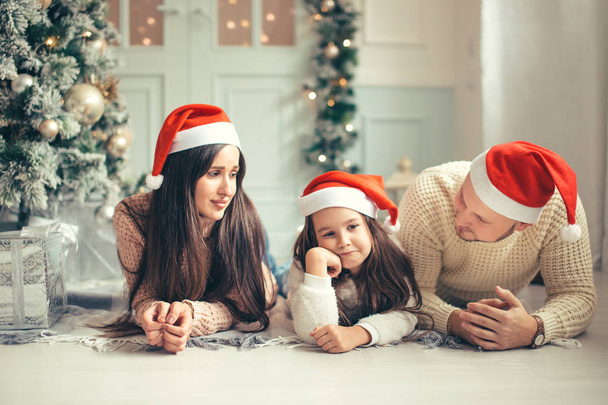 Family in Christmas Santa hats lying on bed. Mother father and baby having fun - Foto, Imagen