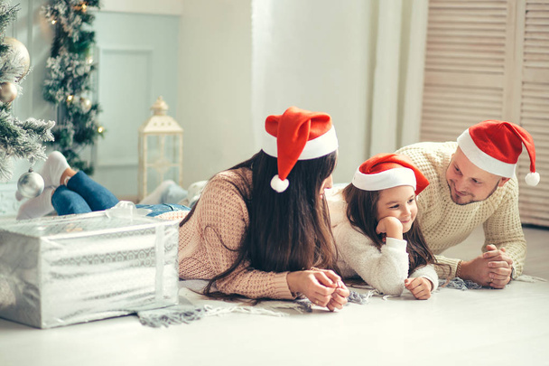 Family in Christmas Santa hats lying on bed. Mother father and baby having fun - Foto, Imagem