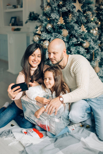 Young happy family of four taking a photo of themselves by a fireplace - Photo, image
