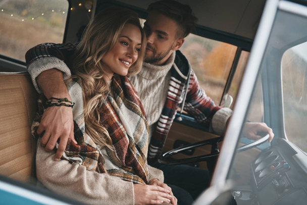 embracing young couple in love enjoying travel in vintage car - Фото, изображение