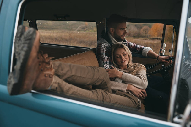 jovem casal apaixonado desfrutando de viagens em carro vintage, mulher descansando e deitado em seu namorado
  - Foto, Imagem