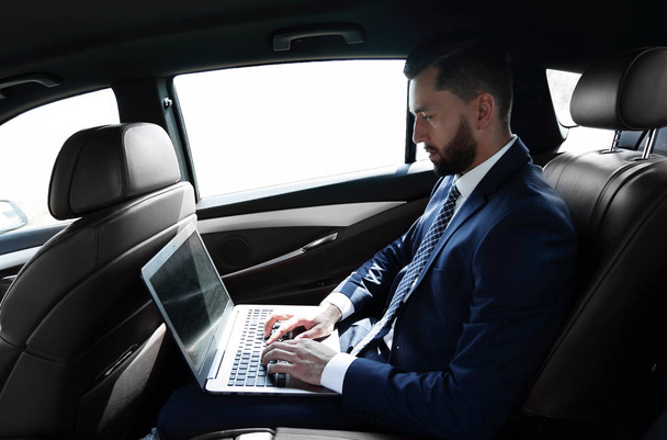 businessman using a laptop in the backseat of a car - Zdjęcie, obraz