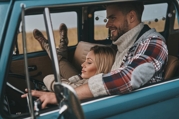 young couple in love enjoying travel in vintage car, woman resting and lying on her boyfriend  - Photo, image