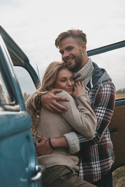 cheerful beautiful couple embracing outdoors near retro style mini van car - Valokuva, kuva