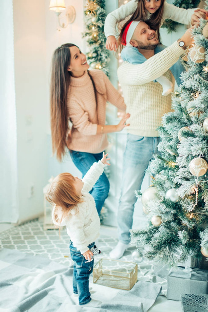 Cute girl and her mother decorating firtree on Christmas eve - Foto, Bild