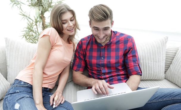 Happy modern couple surfing the net and working on laptop at home - Фото, изображение