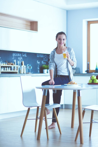 Young woman with orange juice and tablet in kitchen. - Foto, immagini