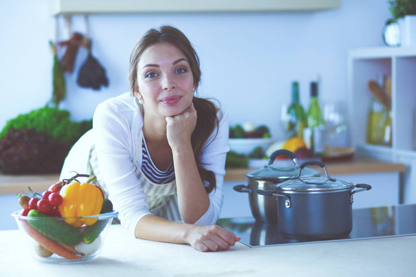 Young woman standing near desk in the kitchen. Young woman . - 写真・画像