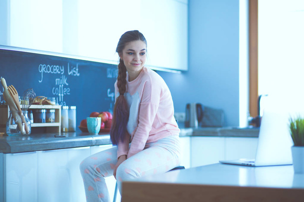 Young woman sitting on table in the kitchen. - Foto, immagini