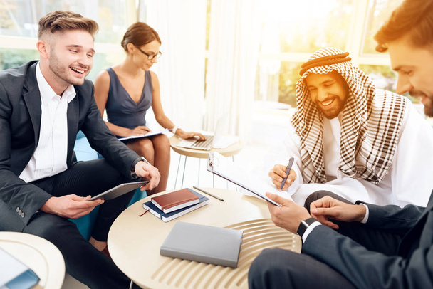 Ένας Άραβας επιχειρηματίας συζητά μια επιχειρησιακή διαπραγμάτευση με τους επιχειρηματικούς εταίρους του. - Φωτογραφία, εικόνα
