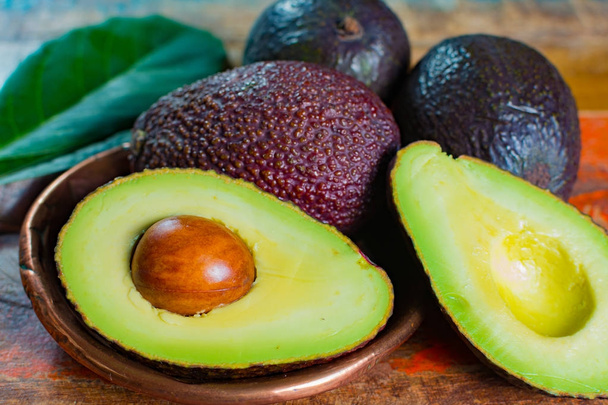 Здорова вегетаріанська їжа зелений стиглий авокадо новий урожай з листям на кам'яних тарілках з орнаментом крупним планом
 - Фото, зображення