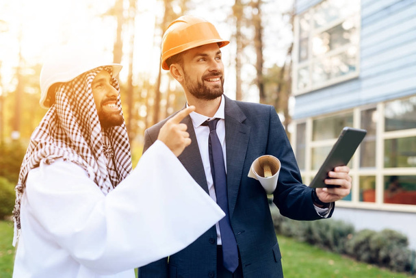 Arap bir işadamı için inşaat planı kask içinde adam gösterir. - Fotoğraf, Görsel