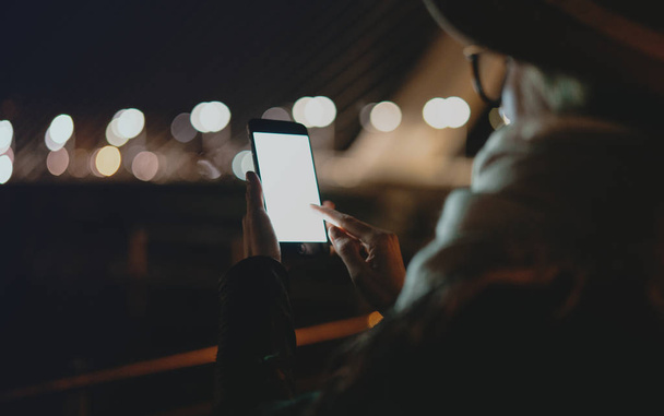 Περικομμένη εικόνα γυναίκας κρατώντας το κινητό τηλέφωνο με οθόνη χώρο κενό αντίγραφο για σας μήνυμα κειμένου ή διαφημιστικό περιεχόμενο, γυναικείου σερφ του ιστού στο smartphone, ενώ χαλαρώνετε σε εξωτερικούς χώρους. - Φωτογραφία, εικόνα