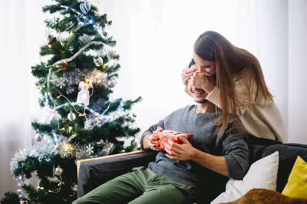 christmas holiday couple happy young woman surprise boyfriend cover his eyes - Fotó, kép