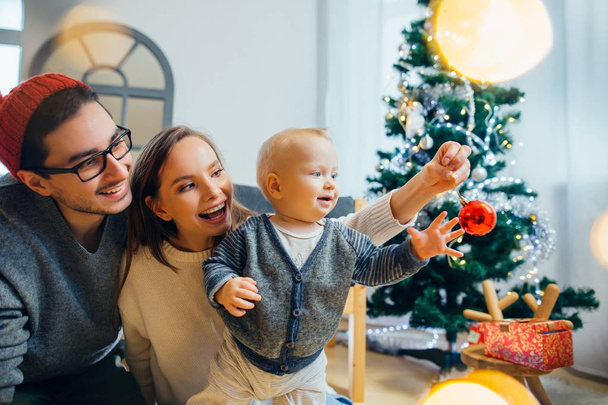 Happy family playing with Christmas balls at home - Zdjęcie, obraz