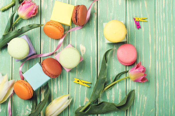 Belles tulipes avec des macarons colorés sur fond de bois verdoyant. Espace de copie. Pose plate
. - Photo, image