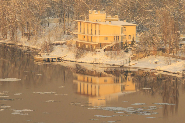 дом покрыт снегом на берегу реки
 - Фото, изображение