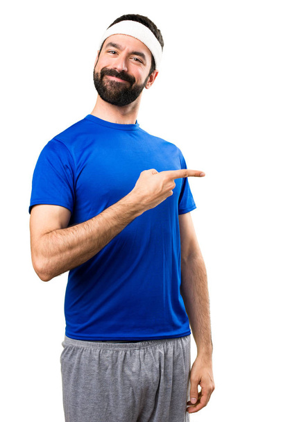 Смешной спортсмен указывая на боковую сторону на изолированном белом бэкгре
 - Фото, изображение