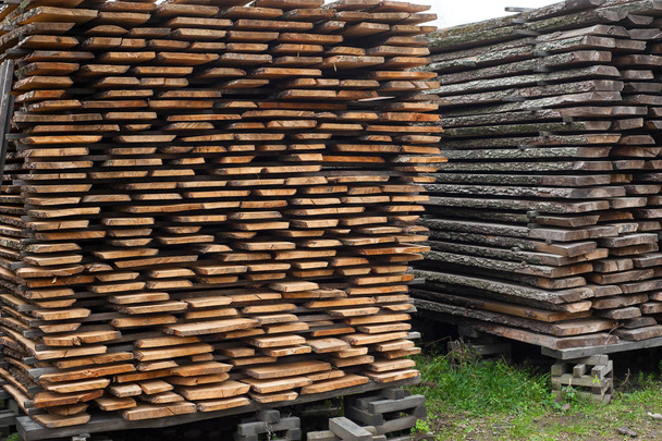 Folded wooden brown and gray planks in a sawmill. Piled alder bo - Photo, Image