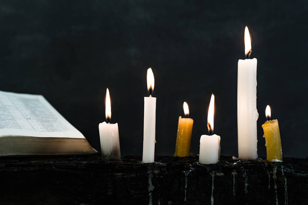 Crocifisso biblico e perline con una candela su un vecchio tavolo in legno bruciato. Bellissimo background. Concetto di religione
. - Foto, immagini