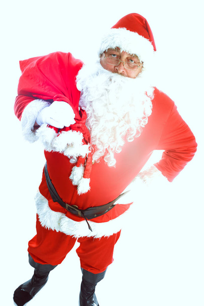 Real Santa Claus carrying big bag full of gifts, isolated on white background - 写真・画像
