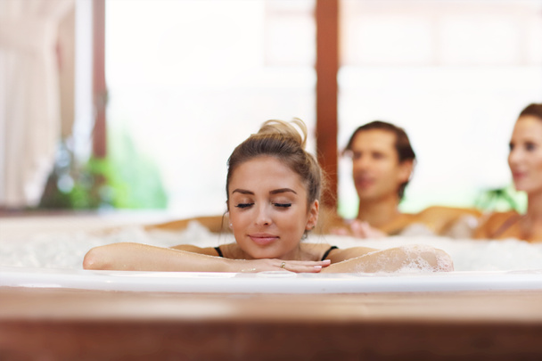 Group of friends enjoying jacuzzi in hotel spa - Photo, Image