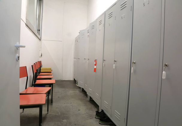 metalen lockers en sommige plastic stoelen in de kleedkamer van een fabriek - Foto, afbeelding