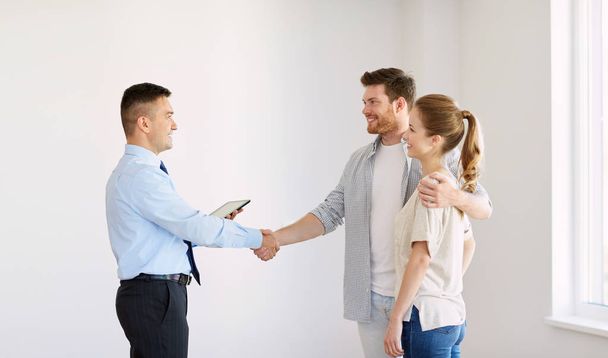 man and realtor shaking hands at new home - Foto, afbeelding