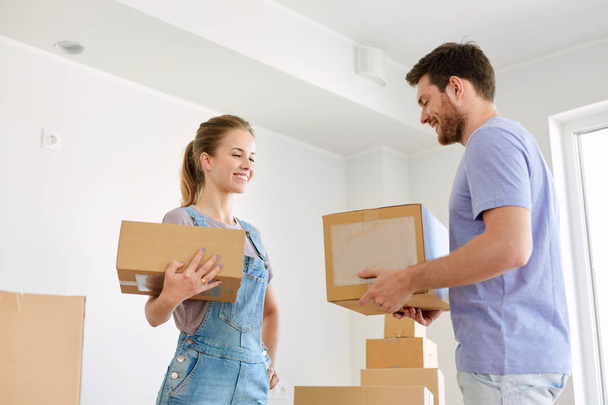 happy couple with boxes moving to new home - 写真・画像