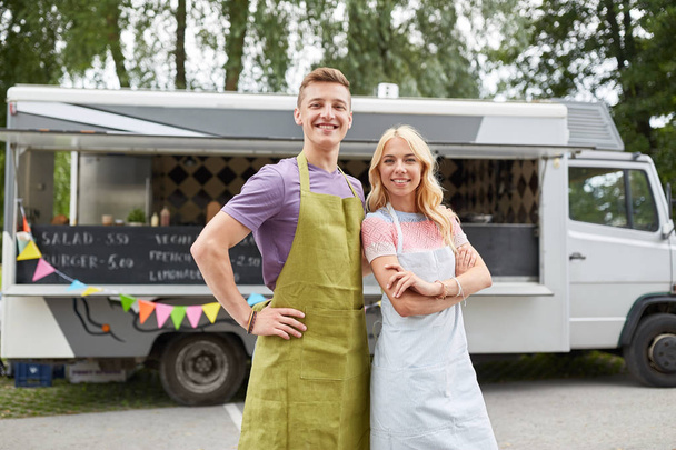 feliz pareja de jóvenes vendedores en camión de comida
 - Foto, Imagen