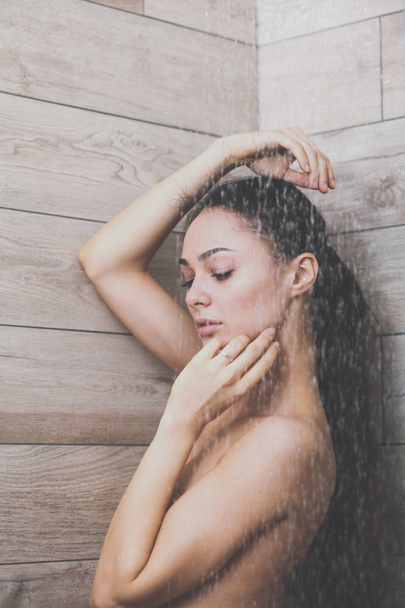 Young beautyful woman under shower in bathroom. - Photo, Image