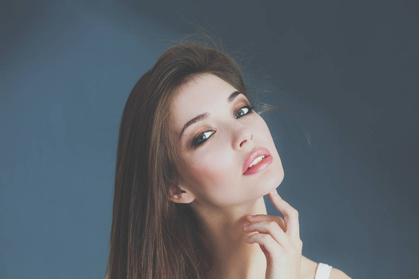 Portrait of beautiful young woman face. Isolated on gray background. - 写真・画像