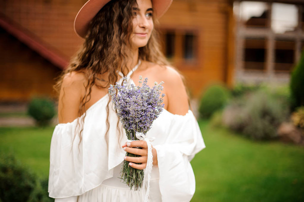 Beautiful woman dressed in white dress with bouquet of lavender - Fotó, kép