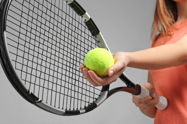 Woman with tennis racket and ball on grey background - Фото, зображення