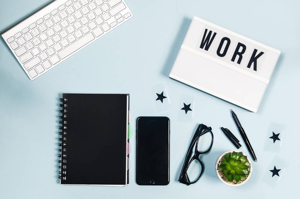 Top view business and freelance items: keyboard, smartphone, pen, glasses, succulent, keyboard frame with word Focus on blue background  - Foto, Imagen