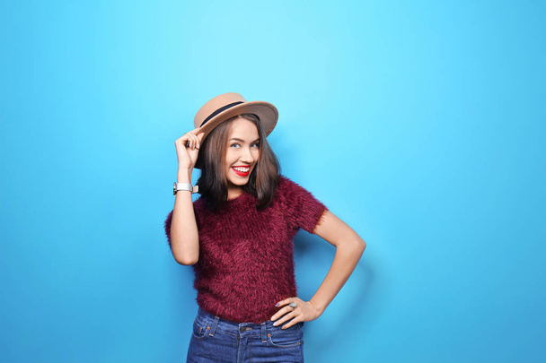 Attractive hipster girl in hat on color background - Zdjęcie, obraz