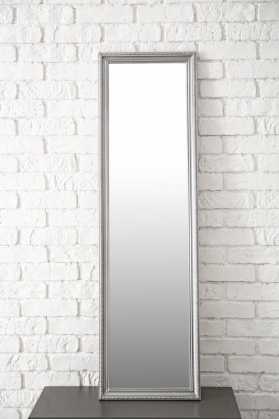 Espelho moderno no suporte perto da parede de tijolo
 - Foto, Imagem