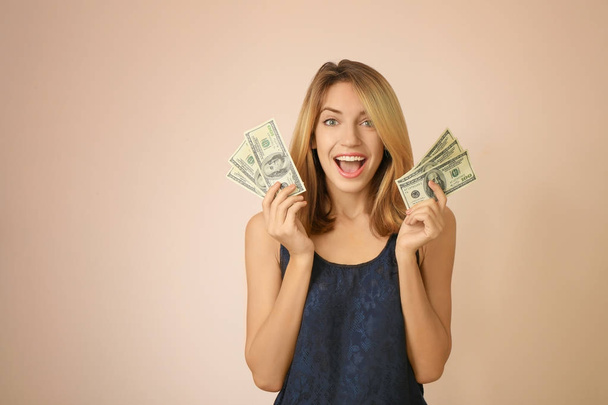 Happy young woman with dollar banknotes on color background - Photo, image