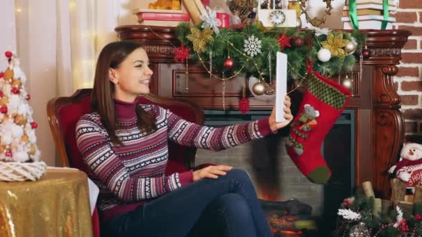 Tablet bilgisayarda chat yapan kadın. Noel arifesinde şöminenin yanında oturan kadın dijital tablet için video sohbet etmek kullanma. - Video, Çekim
