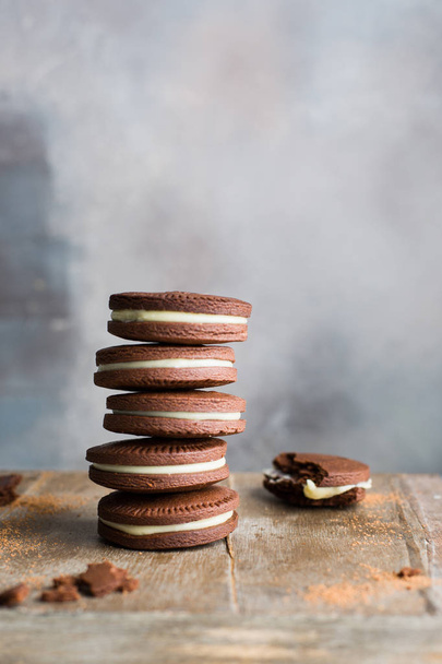 Chocolate cookies with cream. Traditional American popular homemade cookies. A stack of cookies on a wooden background with a bottle of milk. - Fotografie, Obrázek