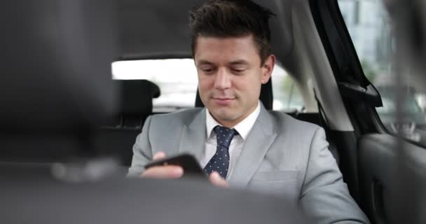 Businessman in taxi cab using smartphone - Filmati, video
