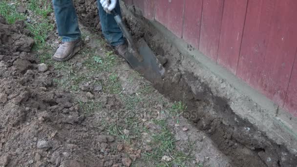 Trabajador excavando trinchera cerca de la antigua casa de madera fundación
 - Metraje, vídeo